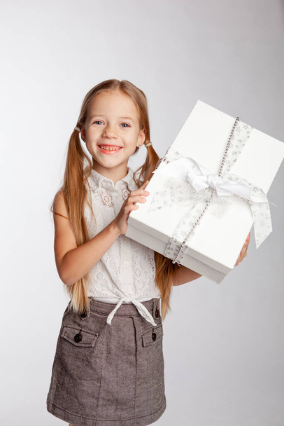 щаслива дівчина тримає подарунок у великій білій коробці з бантом
 - Фото, зображення