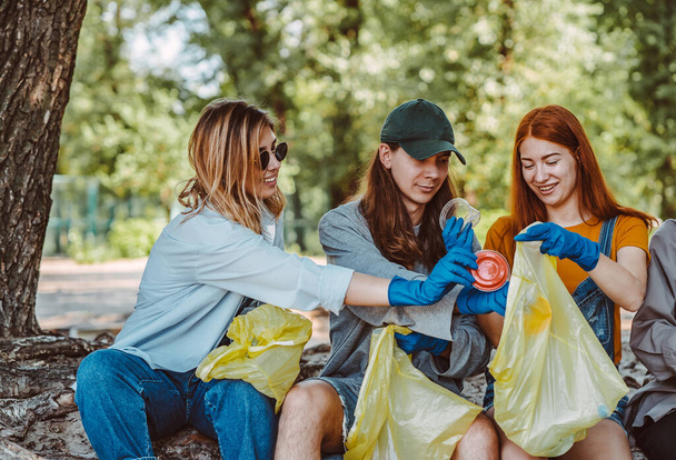 Ομάδα ακτιβιστών φίλοι μαζεύουν πλαστικά απόβλητα στο πάρκο. Προστασία του περιβάλλοντος. - Φωτογραφία, εικόνα