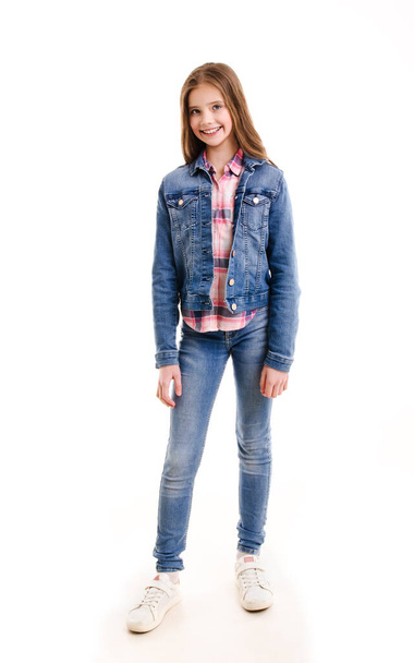 Portrait of adorable smiling little girl child preteen standing in jeans isolated on a white background - Photo, Image