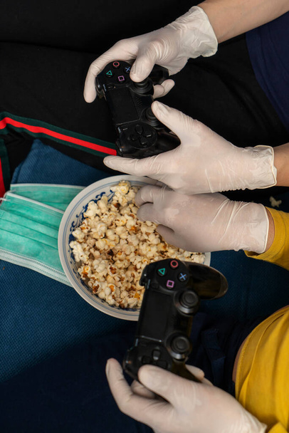 Un couple resté ensemble à la maison, isolé à cause d'une pandémie COVID-19, jouant à des jeux vidéo et mangeant des popcorns
 - Photo, image