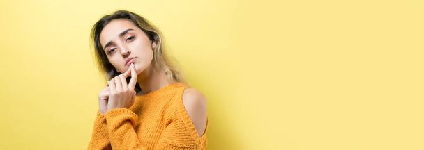 Portrait of a beautiful girl in an orange sweater, looks aside with pensive expression, is considering a plan for further action. - Foto, Imagen