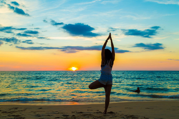 Silhouette segno yoga di donne sane sulla spiaggia tramonto cielo colorato
 - Foto, immagini