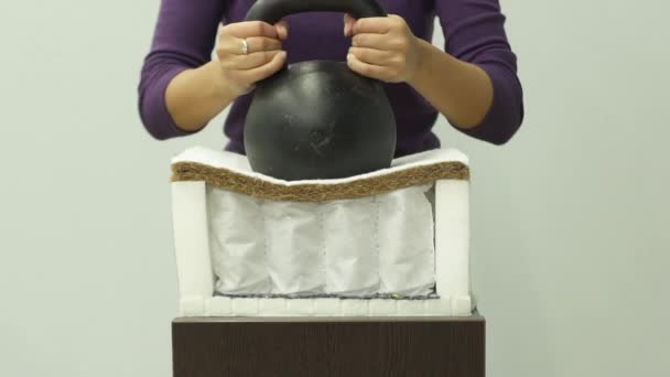Frau legt schweres Gewicht auf eine orthopädische Matratze mit Kokosnuss-Kokos - Filmmaterial, Video