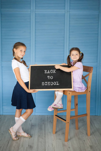 School girl in a uniform and her sister pre-school kid with a chalkboard. Back to school. - Foto, imagen