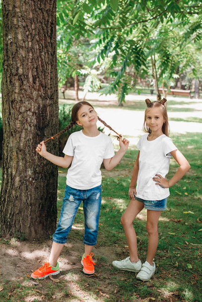Two little girls in white t-shirts having fun in park outdoor. - Valokuva, kuva
