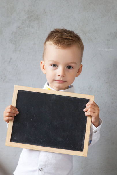Little boy holds a blackboard. back to school concept. Place for text - Foto, Imagem