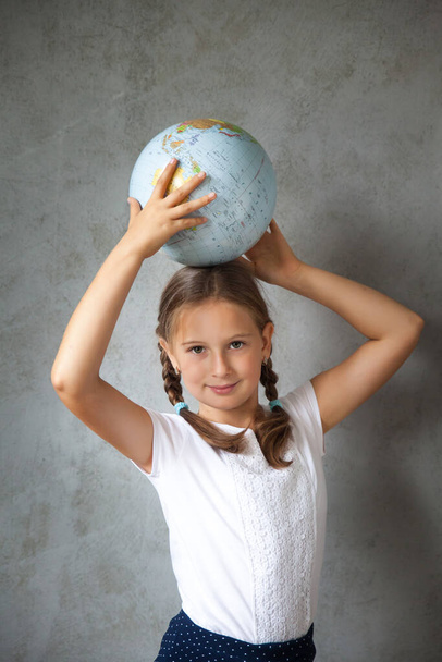 Portrait of a happy school girl with pigtails in a uniform with a globe. Back to school. distance learning from home, Stay at home - Fotoğraf, Görsel