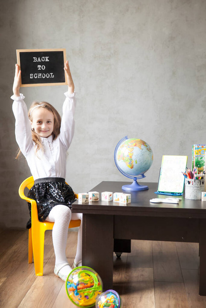 School girl in a uniform holds a blackboard. back to school concept. Distance learning from home - Φωτογραφία, εικόνα