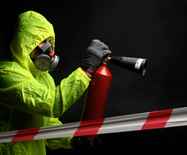 Bombero en respirador atacando un fuego con extintor sobre fondo negro
 - Foto, imagen