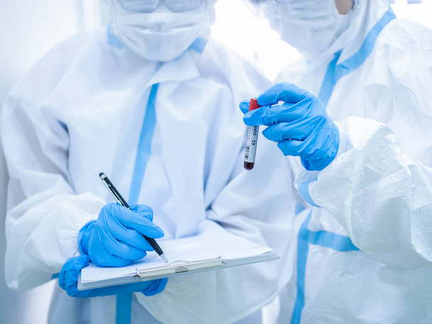 Medico donna indossando maschera e tenendo la provetta prima di raccogliere il campione di sangue dal paziente per lo screening coronavirus. Concetto medico e sanitario
. - Foto, immagini