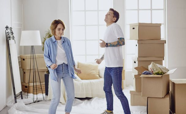 Young happy couple in room with moving boxes at new home - Photo, Image