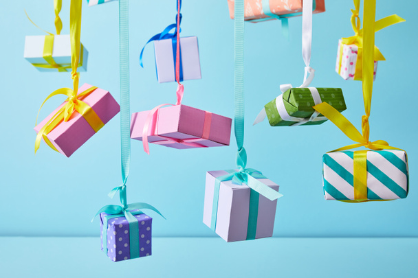 scatole regalo colorate festive appese su nastri su sfondo blu
 - Foto, immagini