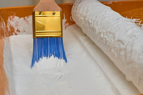 Pincel de madeira para pintura com cabelos azuis em tinta de cor branca
 - Foto, Imagem