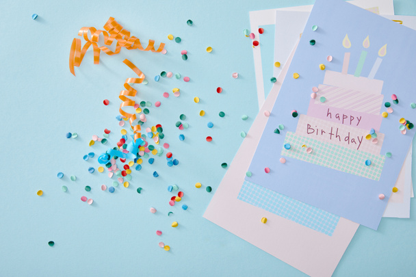 top view of colorful confetti near birthday greeting cards on blue background - Photo, Image