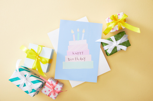 top view of festive colorful gifts and happy birthday greeting card on beige background - Fotoğraf, Görsel