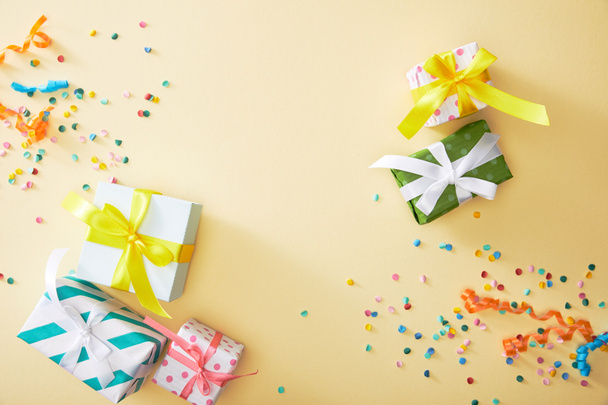 top view of festive colorful confetti and presents on beige background - Foto, Bild