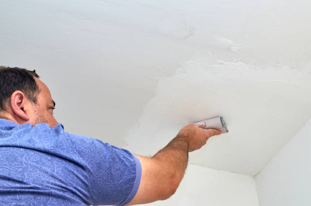 Homem segurando lixa ao polir um teto
 - Foto, Imagem