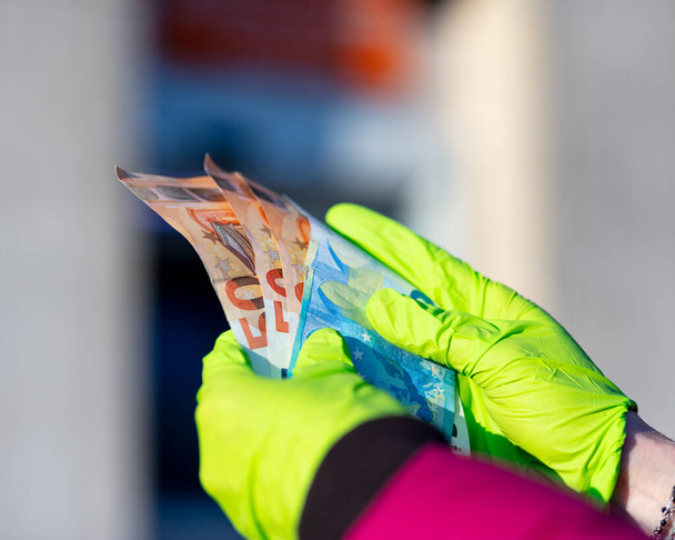 handen van een vrouw met contant geld die ze worstelde om zich terug te trekken uit haar lokale geldautomaat in COVID19 corona virus pandemie tijden - Foto, afbeelding