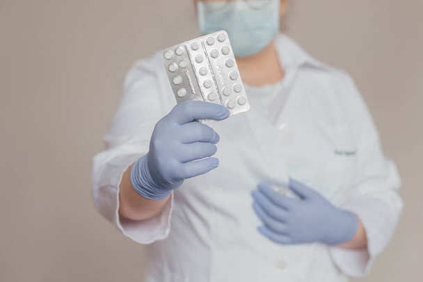 a doctor in a white coat holds a pills in his hand - Photo, image
