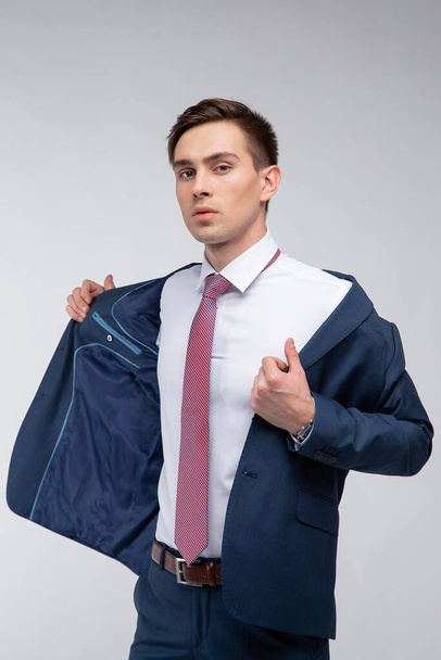 Young, handsome man with dark short hair in a blue suit in a white shirt with a tie on a white background in studio - Foto, Imagem