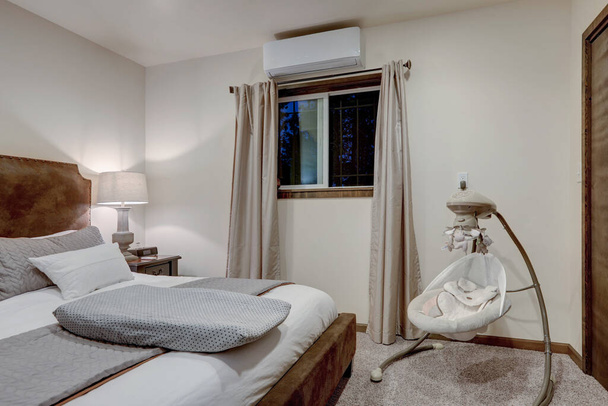 Elegante dormitorio acogedor con cama king size de gamuza marrón, ropa blanca y columpio de bebé, todo en tonos naturales tranquilos
. - Foto, Imagen