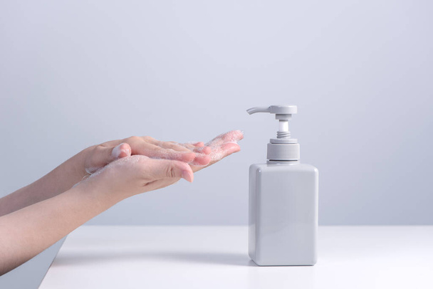 Washing hands. Asian young woman using liquid soap to wash hands, concept of hygiene to stop spreading coronavirus isolated on gray white background, close up. - Photo, image