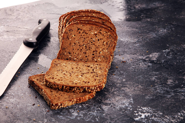 Snijd roggebrood op snijplank. Volkoren roggebrood met zaden op rustieke achtergrond - Foto, afbeelding