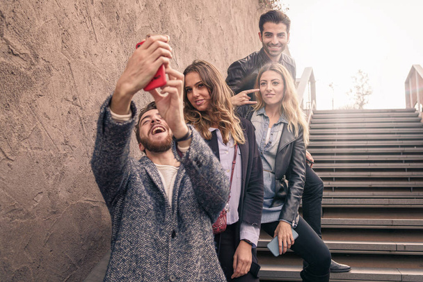 Группа блогеров моды модных влиятелей делает селфи на открытом воздухе. Молодые люди веселятся, фотографируя вместе для своих профилей в социальных сетях
. - Фото, изображение