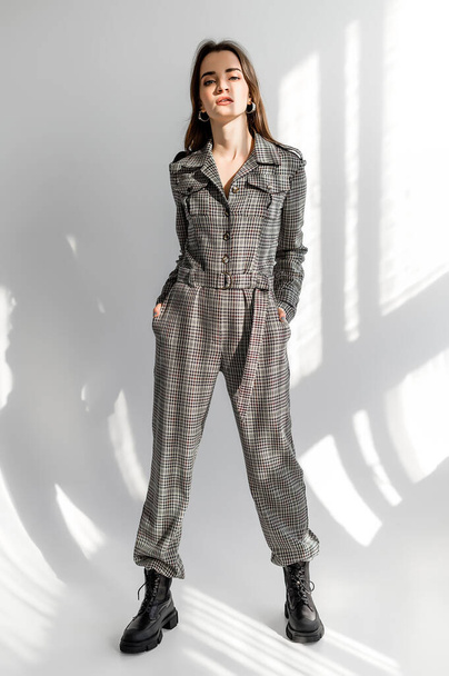 Attractive girl in checkered overalls on a white background. Catalog, clothing magazine - 写真・画像