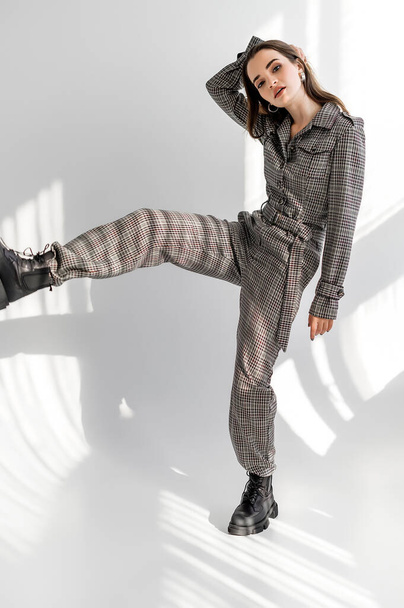 Attractive girl in checkered overalls on a white background. Catalog, clothing magazine - Фото, зображення