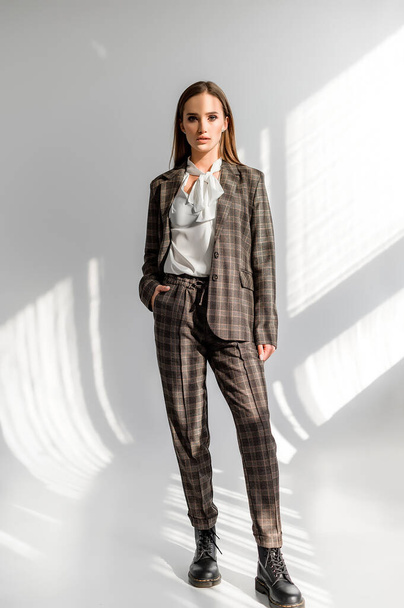 Attractive girl in a checkered suit on a white background. Catalog, clothing magazine - Foto, Imagem