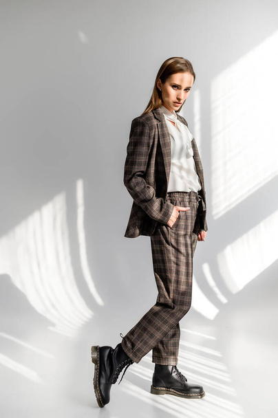 Attractive girl in a checkered suit on a white background. Catalog, clothing magazine - Foto, afbeelding
