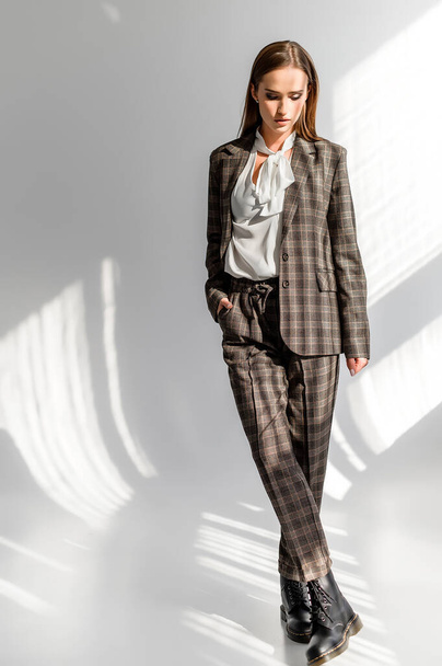 Attractive girl in a checkered suit on a white background. Catalog, clothing magazine - 写真・画像