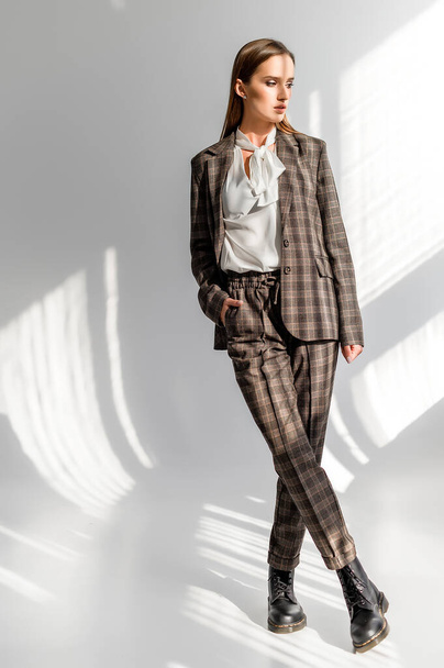 Attractive girl in a checkered suit on a white background. Catalog, clothing magazine - Foto, immagini
