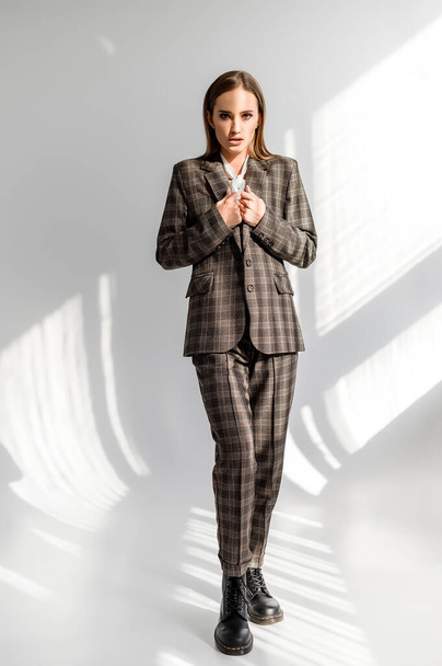 Attractive girl in a checkered suit on a white background. Catalog, clothing magazine - Fotó, kép