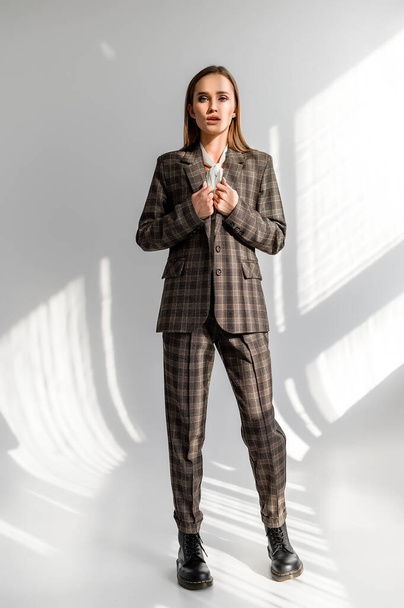 Attractive girl in a checkered suit on a white background. Catalog, clothing magazine - Foto, Bild