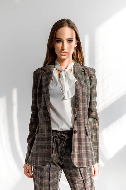 Attractive girl in a checkered suit on a white background. Catalog, clothing magazine - Fotoğraf, Görsel