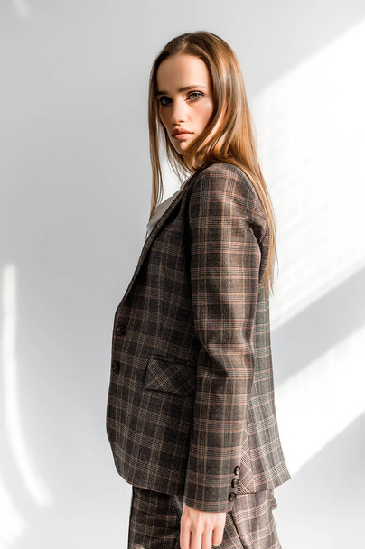 Attractive girl in a checkered suit on a white background. Catalog, clothing magazine - Foto, immagini