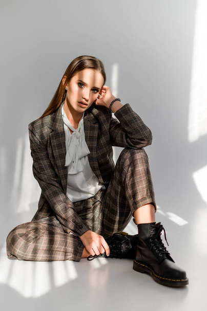 Attractive girl in a checkered suit on a white background. Catalog, clothing magazine - Fotoğraf, Görsel