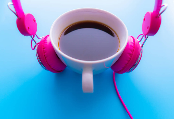 Słuchawki i filiżanka kawy na niebieskim tle. Koncepcja muzyki. Widok z góry z miejsca kopiowania - Zdjęcie, obraz