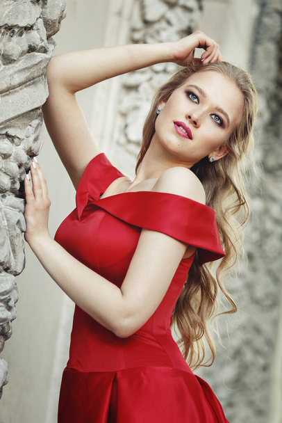 Menina loira bonita em um vestido longo vermelho em um fundo de arquitetura, colunas
 - Foto, Imagem