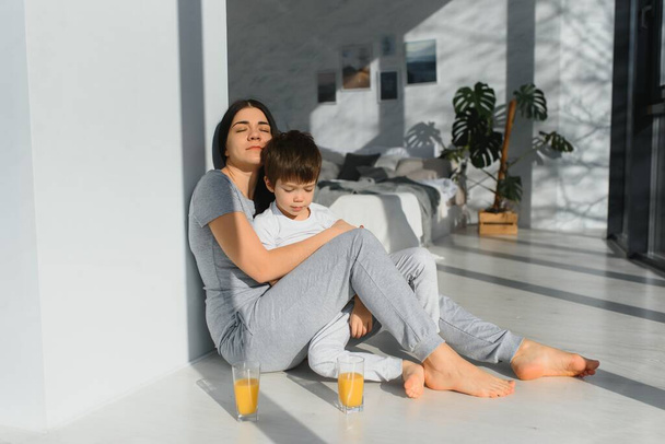 funny mom and son on the floor in the living room, concept motherhood and emotions - Photo, Image