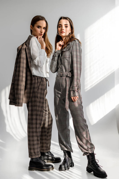 Two girls in a trouser suit and a check overalls on a white background - Fotografie, Obrázek