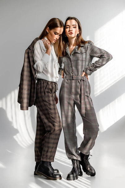 Two girls in a trouser suit and a check overalls on a white background - Φωτογραφία, εικόνα