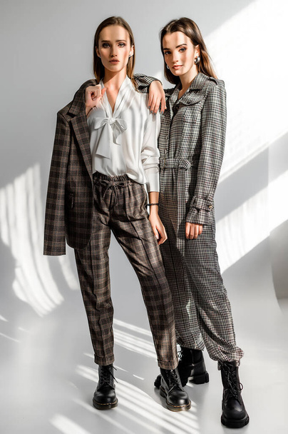Two girls in a trouser suit and a check overalls on a white background - Photo, Image