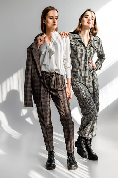 Two girls in a trouser suit and a check overalls on a white background - Foto, Imagen