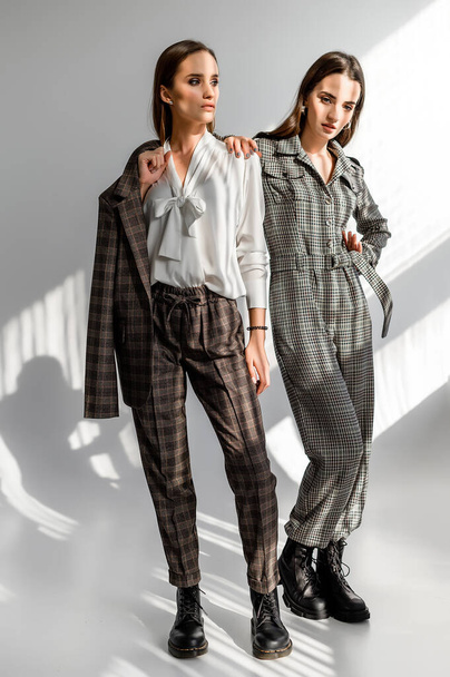 Two girls in a trouser suit and a check overalls on a white background - Valokuva, kuva