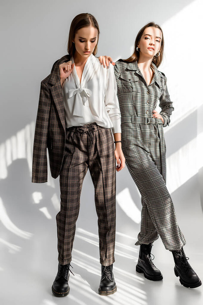 Two girls in a trouser suit and a check overalls on a white background - Photo, Image