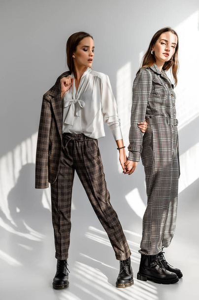 Two girls in a trouser suit and a check overalls on a white background - Foto, afbeelding