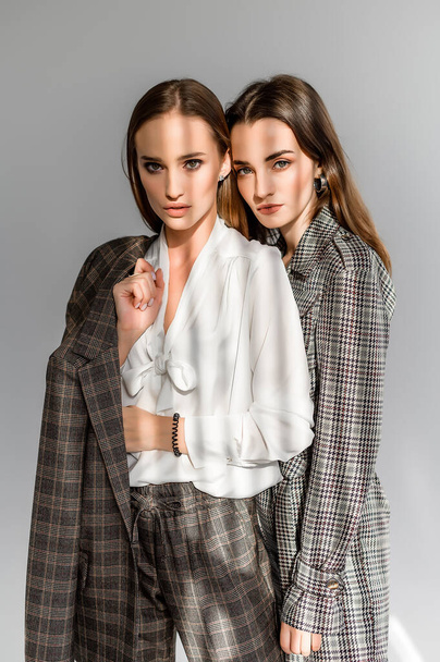 Two girls in a trouser suit and a check overalls on a white background - Fotó, kép